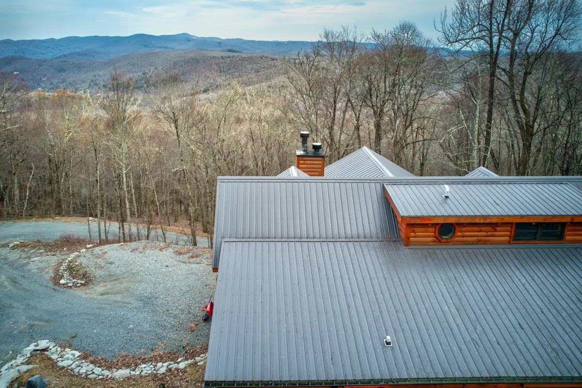 A perspective focused on the home’s roofline set against the dramatic backdrop of bare trees and distant mountains. The composition draws attention to the surrounding wilderness and the variety of outdoor experiences available, from hiking to birdwatching and stargazing.