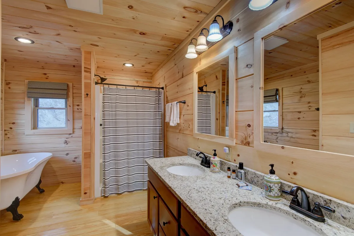 A tranquil bathroom with a freestanding bathtub, double sink vanity, and wooden walls, creating a spa-like oasis. The setup invites long, relaxing baths or efficient morning routines, all in a setting of rustic elegance.