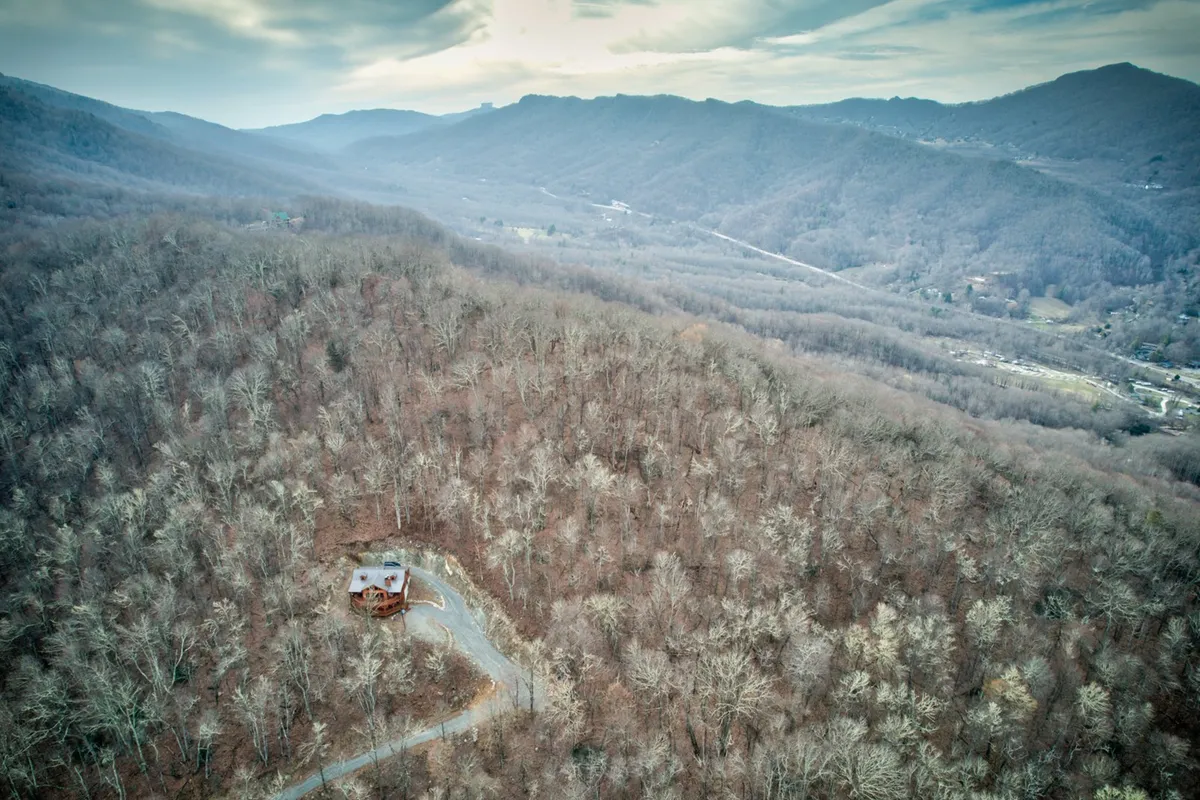 A sweeping view of the house set against a winding road and panoramic mountains. The scene suggests endless opportunities for hiking, exploration, and enjoying the outdoors, with the property seamlessly integrated into its adventurous surroundings.